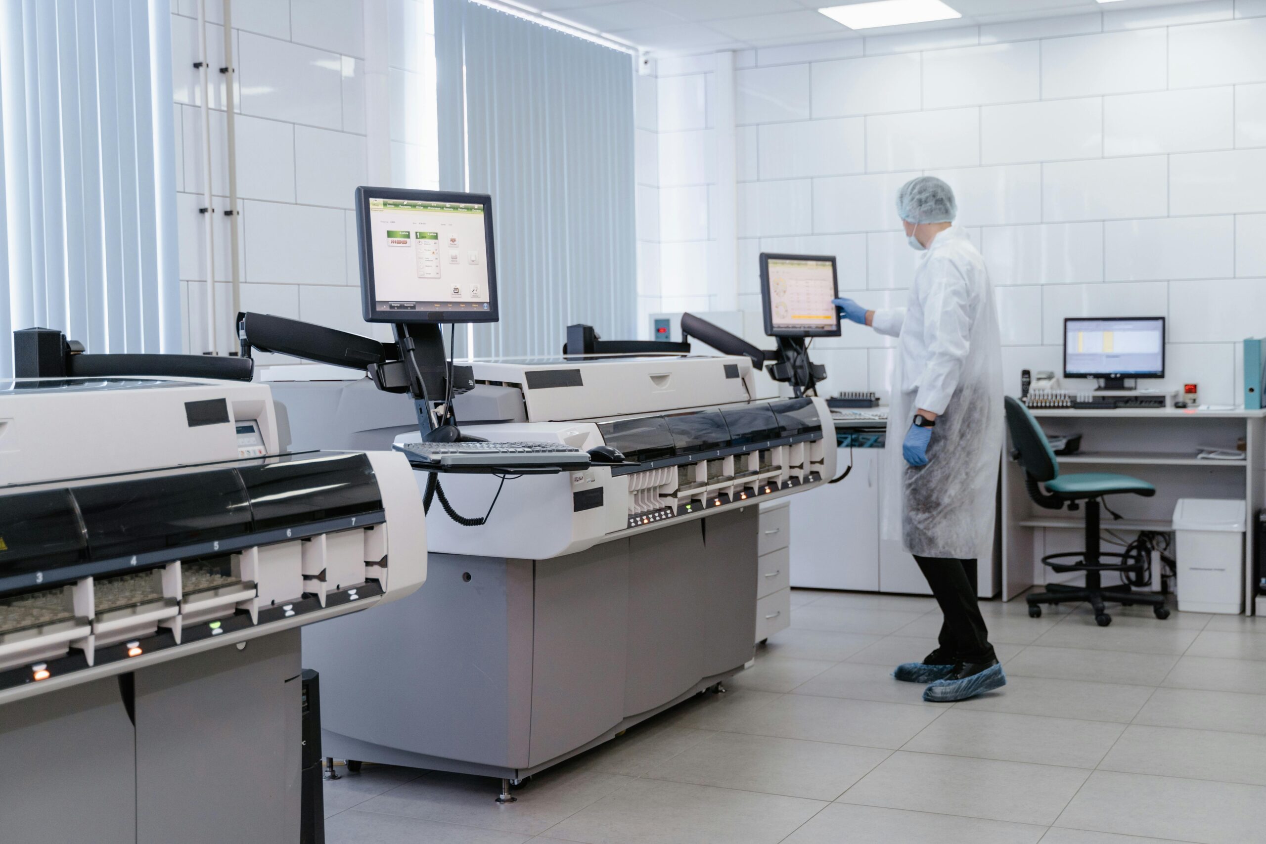 Scientist in a lab gown interacting with equipment in a modern laboratory setting.